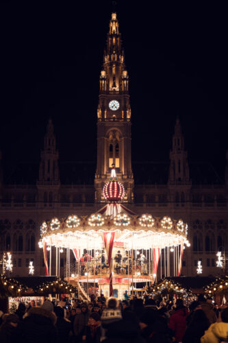 Christmas Market at Vienna City Hall with carousel and children's attractions in the foreground.