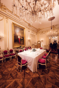 Elegant baroque dining room at Schönbrunn Palace (Schloss Schönbrunn) with red velvet curtains and imperial furniture.