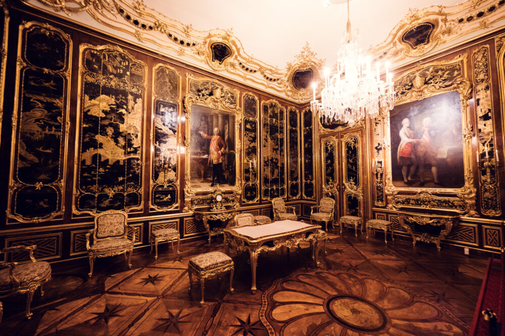 Ornate baroque room at Schönbrunn Palace (Schloss Schönbrunn) with extensive gold decorations, imperial palace interior featuring gilded rococo ornaments and crystal chandeliers.
