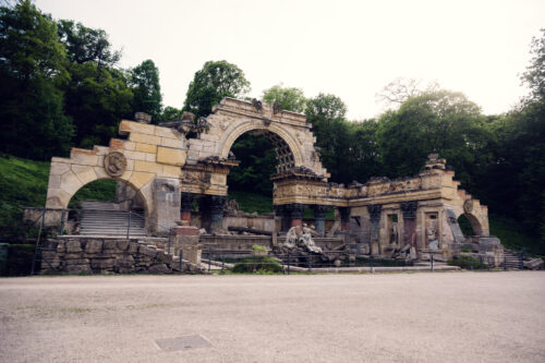 Roman Ruins Fountain Schönbrunn artificial baroque water feature with classical stone arches and decorative basin in landscaped garden setting.