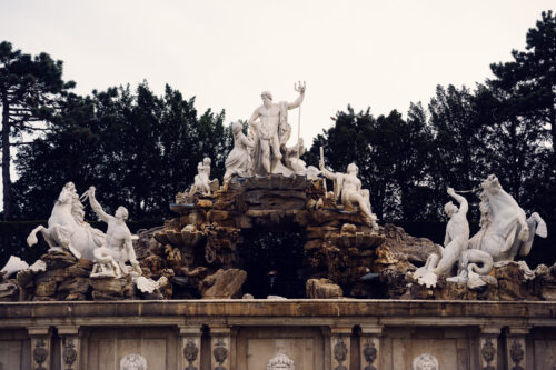 Schönbrunn Neptune Fountain central sculpture with Tritons and horses in formal garden setting.