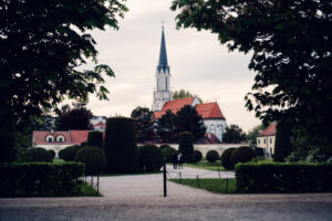 Pfarrkirche Hietzing church spire visible through trees from Schönbrunn Palace gardens with baroque church tower.