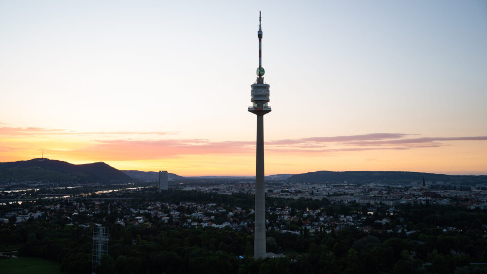 Vienna's Donauturm at sunset, Austria's tallest structure featuring its distinctive tower design with two high-speed elevators and viewing platforms at 155 and 165 meters.