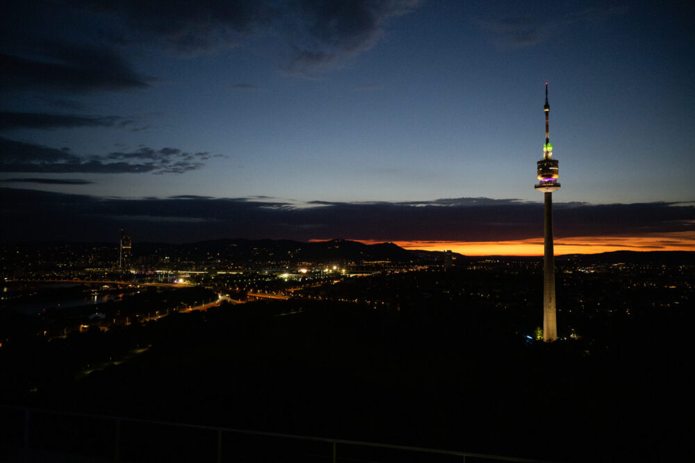 Donauturm Vienna sunset 252 meter tower against orange sky.