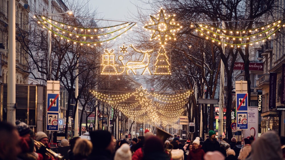 Mariahilfer Strasse Vienna Christmas evening with illuminated holiday decorations festive street lights and seasonal shopping crowds.