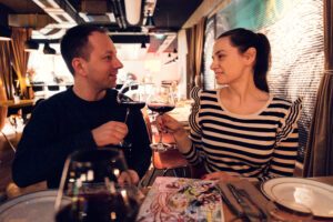 Adriana and Mario cheering with wine at Neni am Prater, celebrating the lively dining atmosphere.
