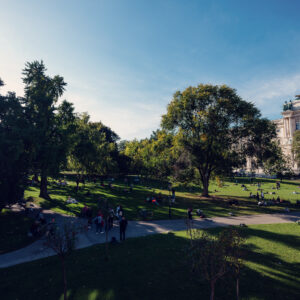Pomeriggio di sole al Burggarten con visitatori sul prato vicino alla Hofburg.