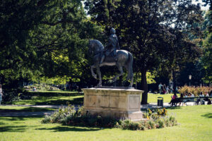 Historic monument in Burggarten, Vienna, surrounded by lush greenery and vibrant flowers.