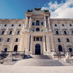 Grand facade of the Hofburg Palace viewed from Burggarten, showcasing Vienna's imperial grandeur.