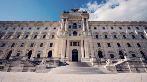 Grand facade of the Hofburg Palace viewed from Burggarten, showcasing Vienna's imperial grandeur.