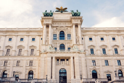 Grand facade of the Hofburg Palace viewed from Burggarten, showcasing Vienna's imperial grandeur.