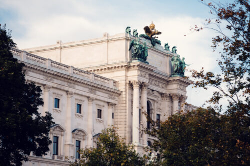 Scenic view of the Hofburg Palace from Burggarten, framed by lush greenery and offering a glimpse into Vienna's regal history.