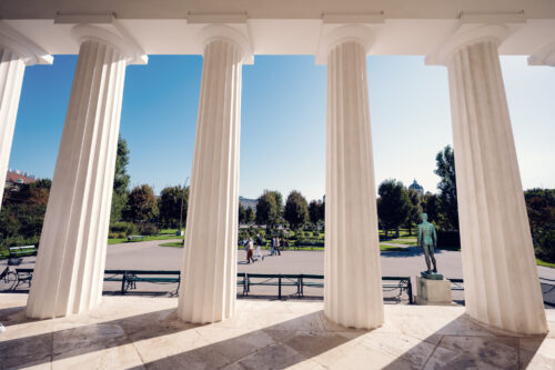 White marble Theseustempel Vienna surrounded by green parkland and trees in Volksgarten setting.