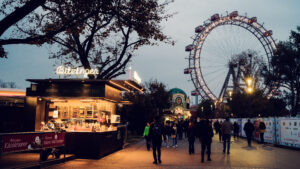 Ikonischer Bitzinger Würstelstand Prater, im Hintergrund das beleuchtete historische Riesenrad Wiens - eine magische Abendstimmung.