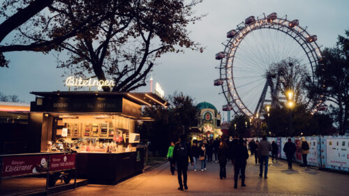 Iconic Bitzinger Würstelstand Prater with Vienna's historic Riesenrad illuminated in the background, creating a magical evening scene.