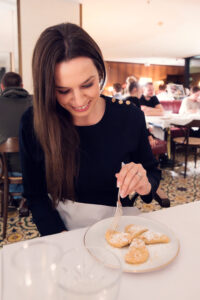 Joyful moment tasting warm plum turnovers (Powidltascherl), her smile revealing the sweet surprise at Meissl & Schadn.