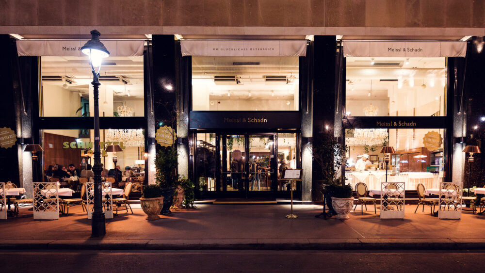 Inviting evening ambiance at Meissl & Schadn captured through elegant windows from Ringstrasse.
