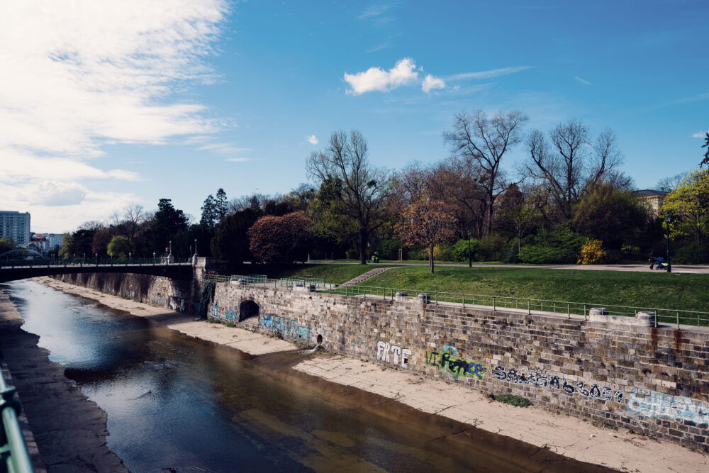 Historic bridge reflections in Stadtpark's calm waters during early hours.