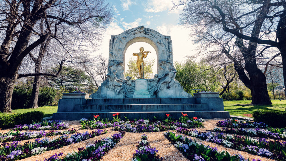 Historic Johann Strauss Monument surrounded by beautiful flowers in Stadtpark, a must-visit photo spot celebrating Vienna's musical heritage.