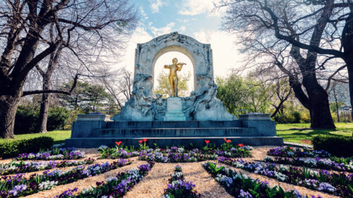 Historic Johann Strauss Monument surrounded by beautiful flowers in Stadtpark, a must-visit photo spot celebrating Vienna's musical heritage.