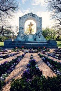 Golden statue of Johann Strauss in Vienna's Stadtpark, capturing the elegance of the Waltz King against a backdrop of lush greenery.