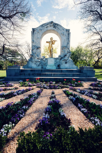 Golden statue of Johann Strauss in Vienna's Stadtpark, capturing the elegance of the Waltz King against a backdrop of lush greenery.