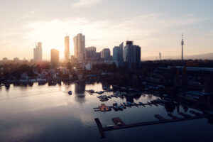 Vienna city skyline during sunset viewed from Alte Donau recreational area with warm evening colors.