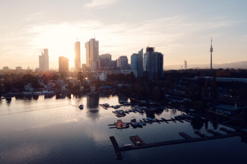 Vienna city skyline during sunset viewed from Alte Donau recreational area with warm evening colors.