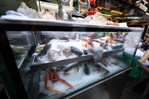 Fresh fish vendors at Naschmarkt presenting daily catches on beds of crushed ice.