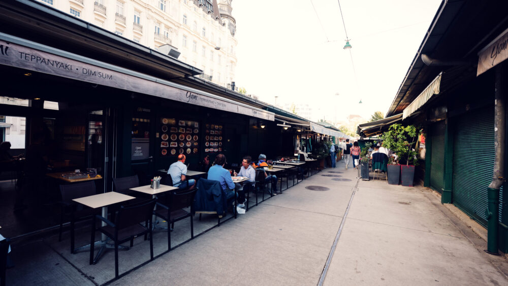 Inviting outdoor seating at Naschmarkt beneath original Art Nouveau structures.