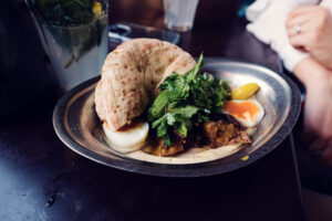 Colorful mezze at NENI featuring homemade hummus, egg, and fresh pita bread.