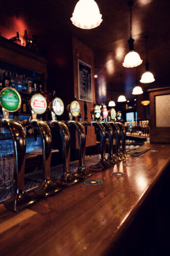 Evening atmosphere at Flanagans draft beer station, where warm lighting illuminates row of traditional tap handles.