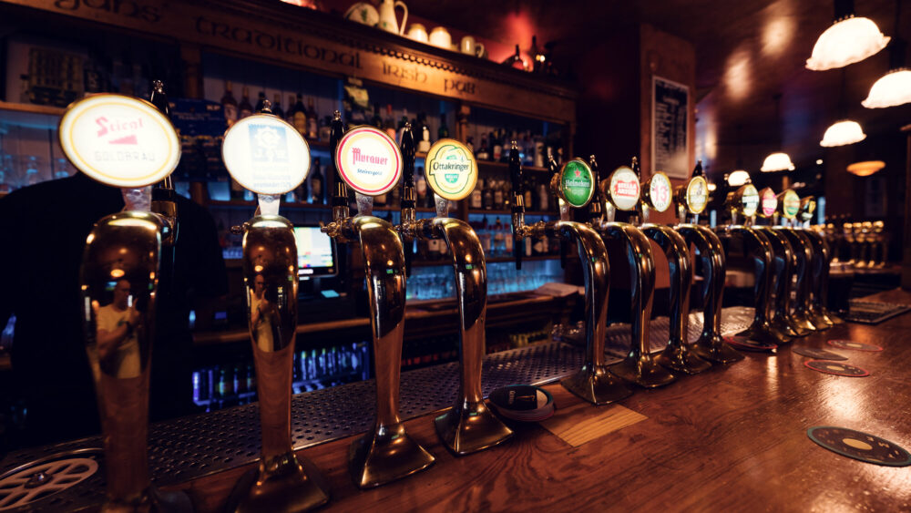 Traditional beer tap station at Flanagans Irish Pub Vienna, where polished brass taps and iconic brand badges showcase authentic pub culture.