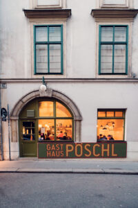 Evening atmosphere at Gasthaus Pöschl entrance, where warm lighting welcomes guests through historic doorway.