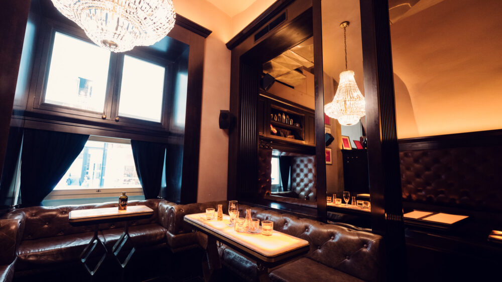 Corner lounge area in Kleinod Bar with vintage leather armchairs and marble side tables.