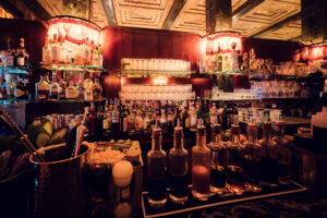 Premium spirits collection at Loos American Bar Vienna, where carefully curated bottles line historic shelves against original marble backdrop.
