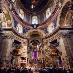 Interno riccamente decorato della Peterskirche di Vienna, con elaborate colonne di marmo, intagli del pulpito e la famosa pianta ovale tipica dell'architettura barocca.