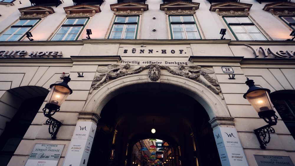 Historic entrance archway to Sünnhof's umbrella passage, where traditional Viennese architecture frames vibrant art installation.