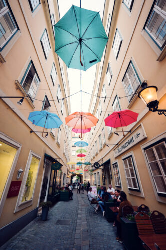 Rainbow umbrella canopy at Sünnhof Vienna, creating magical light patterns on historic cobblestones.