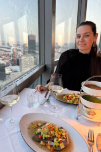 Gourmet Tafelspitz plate at Das Turm restaurant 170 meters above Vienna, garnished with chive sauce and rösti potatoes, with panoramic views of the illuminated Danube River.