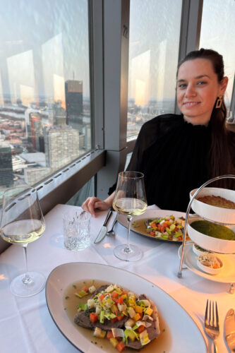 Gourmet Tafelspitz plate at Das Turm restaurant 170 meters above Vienna, garnished with chive sauce and rösti potatoes, with panoramic views of the illuminated Danube River.
