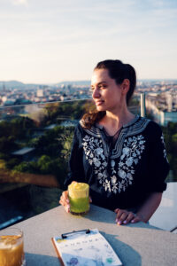 Adriana enjoying cocktail at Aurora Rooftop Bar Vienna Austria, elevated cocktail experience with panoramic city views.
