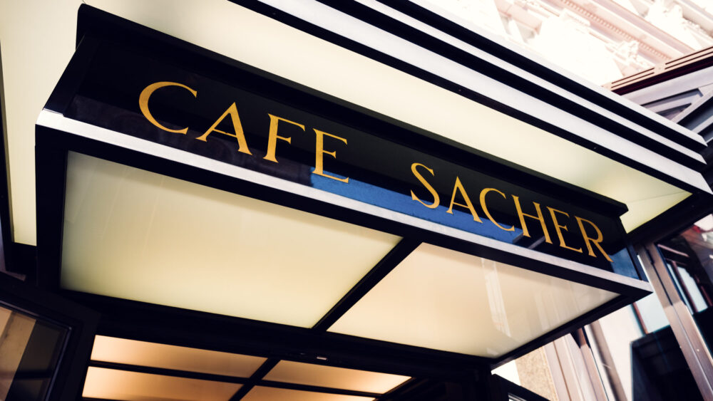 Close-up of the original Café Sacher sign with golden lettering.