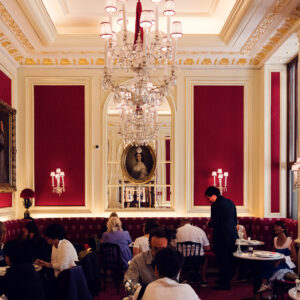 Elegant interior of Café Sacher Vienna with red velvet chairs, crystal chandeliers and classic marble tables.