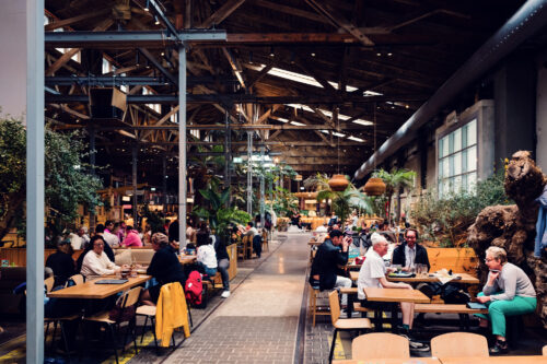 Interior of Gleis//Garten Vienna showing the industrial-chic design with exposed brick walls, high ceilings, and communal seating areas perfect for social dining.