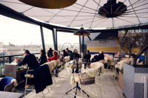 Modern lounge furniture at Lamee Rooftop Bar against Vienna's architectural backdrop.