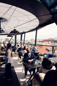 Outdoor seating area at Lamee Rooftop Bar Vienna with city skyline backdrop.