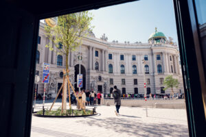 Michaelerplatz Vienna with the Roman excavation site in the foreground and the ornate Baroque facade of Hofburg Palace (Michaelertrakt) featuring its iconic dome and architectural details.