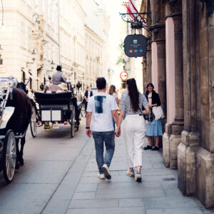 Adriana and Mario walking through Vienna's Old Town (Altstadt) with traditional horse-drawn carriages (Fiaker) in foreground.