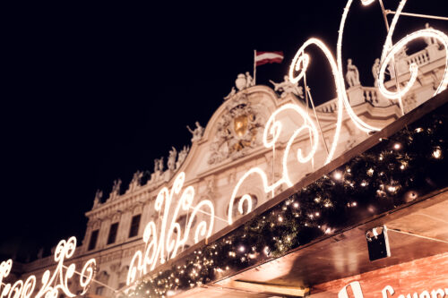 Ornament and gift chalets at Belvedere Christmas Village with UNESCO World Heritage palace in background.